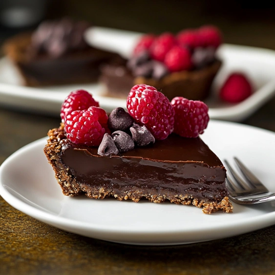 A slice of chocolate cake with raspberries on top.