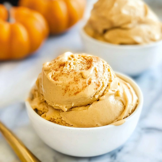 Two bowls of ice cream with pumpkins in the background.