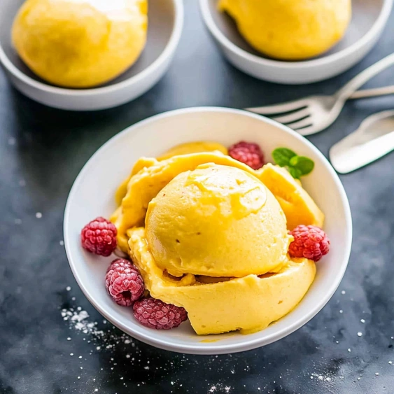 A bowl of ice cream with raspberries on top.
