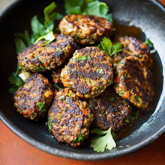 A bowl of meatballs with herbs.