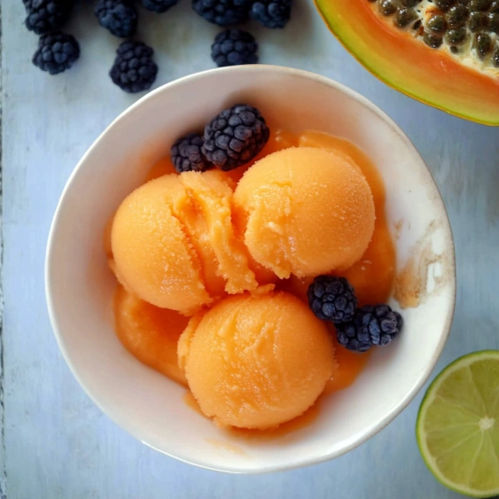 A bowl of orange and blue fruit.