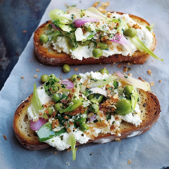 Two pieces of bread with vegetables on top.