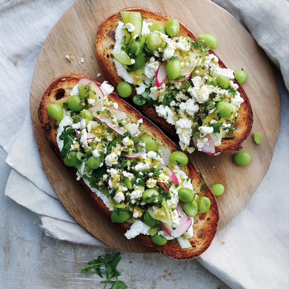 Two slices of bread with green beans and cheese on top.