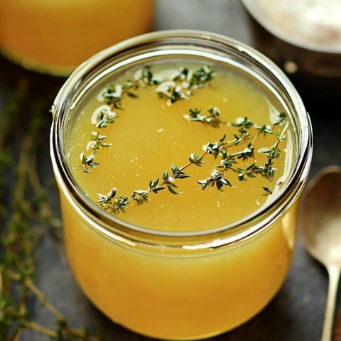 A jar of honey with herbs in it.