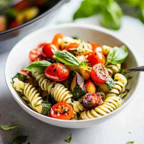 A bowl of pasta with tomatoes and basil.